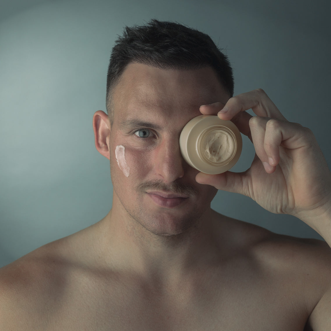 Male holding the water bomb eye cream to the eye